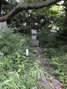 wooded area with footpath to a small stone temple