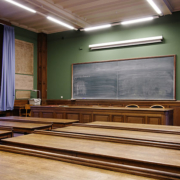 empty classroom with chalkboard in the forefront and wooden desks